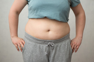 fat girl on diet, Overweight fat woman with a little portion of food trying to lose weight. Extreme diet,woman's hand holding excessive belly fat, the concept of weight loss