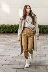 Portrait shooting of a stylish girl. Beige shades. Trends of spring and summer 2019. Pants of cork.Trench cloak, a wide jacket.