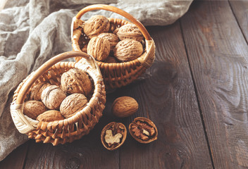 walnuts in wicker baskets on a wooden background. nuts on the table. background with walnuts.