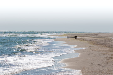 Wooden deck chair on deserted sand beach and sea with waves