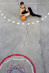 pregnant girl on the basketball court sits on the ball view from the top.