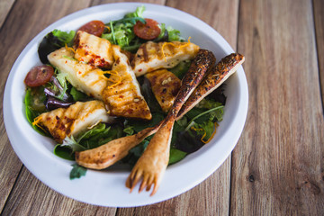 Grilled Halloumi Cheese salad witch tomatoes and lettuce in white plate in wooden background. healthy food