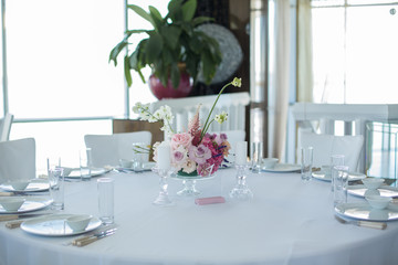Event white restaurant table served and decorated with delicate fresh flowers