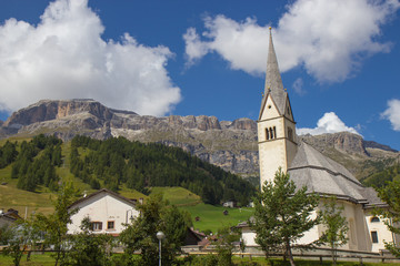 Fototapeta na wymiar View of Church surrauded by mountains in Arabba village, Dolomites Alps, Italy