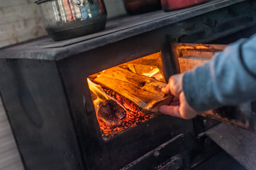 Man putting log to wood burning stove