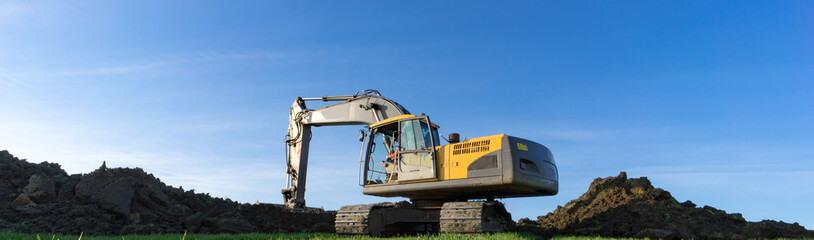 Banner - Bagger befindet sich auf einer Baustelle zwischen Erdhügel