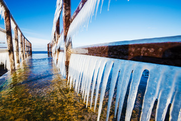 Snow-covered old rusty pier on a clear sunny day. Ice fragments close-up. Baltic Sea, Latvia - Powered by Adobe