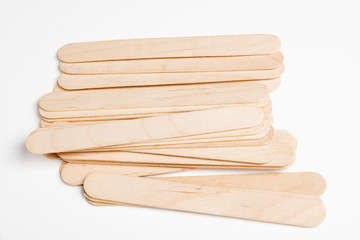 A set of plain and unused wooden crafts sticks strewn artfully on a white background.