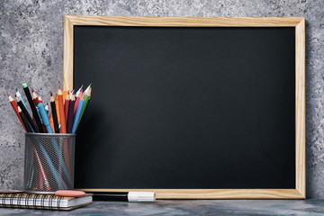 A set of various pencils, pens and a chalk board with copy space