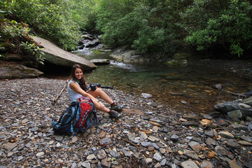 A young woman sitting by a trailside stream in the Great Smoky Mountains National Park, Tennessee, in early summer.