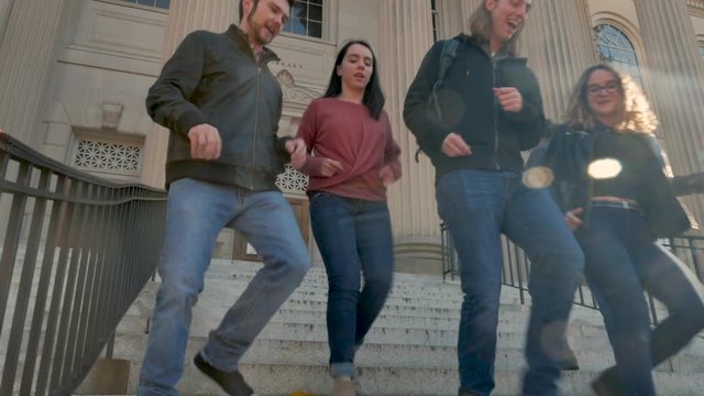 Four college friends walking down steps while passing another student walking up