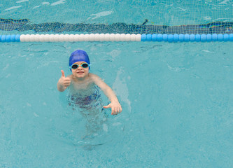 top view of a 7-year boy playing and swimming in the swimming pool smiling