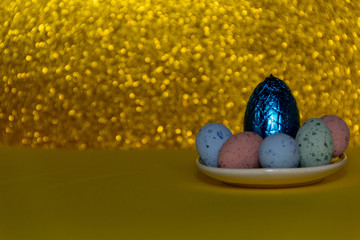 Blue egg on a golden background, surrounded of colorful eggs