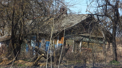 Abandoned rickety wooden house in a withered garden on derelict village