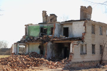 Fototapeta na wymiar Damaged destroyed two-storey brick house ruins