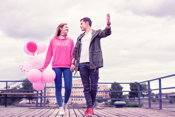 Romantic short-haired guy looking on his girlfriend and carrying her hand
