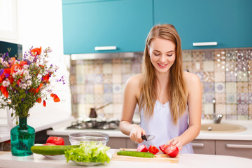 Obraz na płótnie Canvas beautiful girl making salad in the kitchen