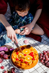 Female cut pie with oranges for a event day on picnic checked cloth