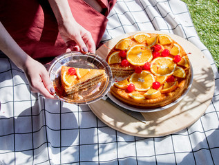 Female holding a piece of a cake on plate.
