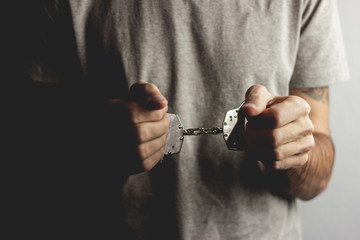 young man hand handcuffs on dark background