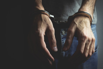 young man hand handcuffs on dark background