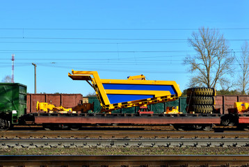 Logistics transportation heavy mining dump truck by rail. Yellow mining truck disassembled into parts, cab, body, electric motor, drive, wheels, loaded onto a cargo railway platform.