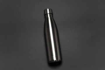 Steel thermo bottle for water with lid against black background.