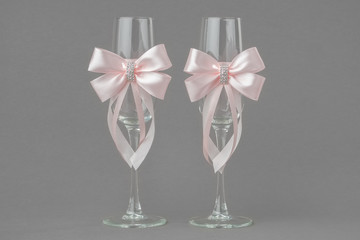 Two wedding wine glasses decorated with pink ribbons.