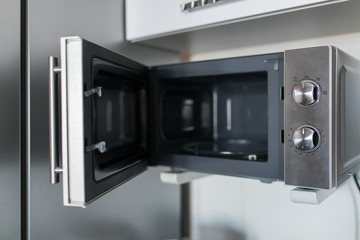 Empty microwave oven with open door in kitchen