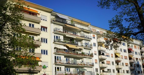 Häuserfassade mit Balkonen und Markisen mit blauem Himmel an einem sonnigen Tag