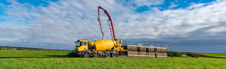 Anlieferung von Frischbeton durch einen gelben Betonmischer auf einer Baustelle