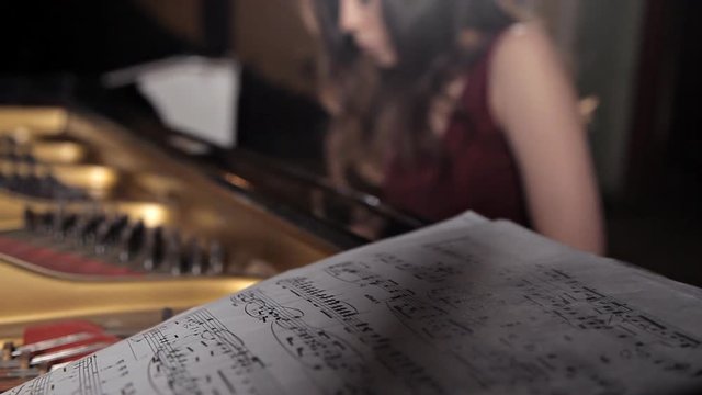The girl sits at the piano and learns music, notes. Music, performance, sheet with notes