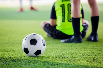 soccer ball on green artificial turf with blurry soccer players
