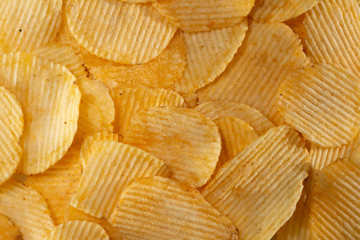 Close-up lot of tasty rippled yellow potato chips background