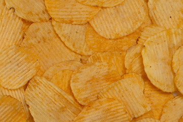 Close-up lot of tasty rippled yellow potato chips background