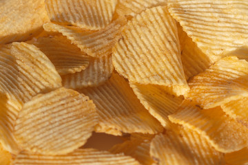 Close-up lot of tasty rippled yellow potato chips background