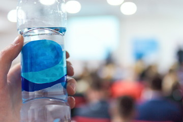 Business man on conference holding and drinking watter bottle.