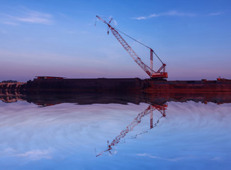 Mirror reflection of Crawler cranes used for rebuilding bridges  near the river