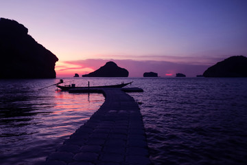 Sunset view of Local boat moored on floating pier with ocean landscape and island