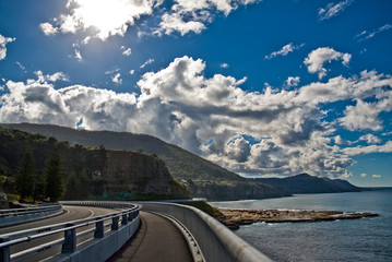 The Sea Cliff Bridge, Illawarra, NSW, Australia winding its way around the headland with white clouds. Beautiful Water Views of the Wollongong Coastline Looking North