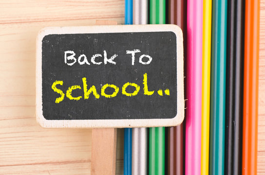 word BCK TO SCHOOL written on wooden signage over colorful pencil on desk