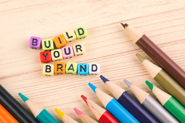 Colorful cube word BUILD YOUR BRAND on wooden background for advertising and commercial marketing concept