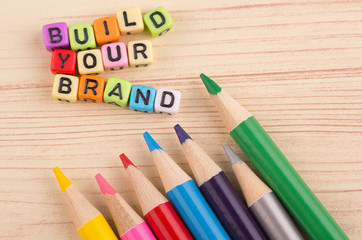 Colorful cube word BUILD YOUR BRAND on wooden background for advertising and commercial marketing...