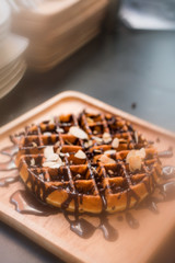 waffles with chocolate sauce on wooden plate. vintage concept
