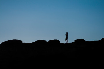 Silhouette of a Man on Top of a Cliff