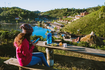 Fototapeta na wymiar The Girl travel on the mountain. She is watching the scenery beautiful of Ban Rak Thai village, Drink coffee and eat food, snack in the morning.