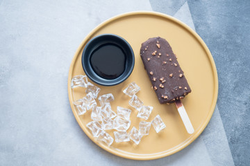 Chocolate ice cream bar with nuts on yellow plate