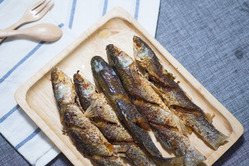 Fried mullet fish served on wood tray