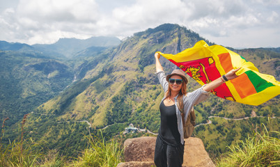 Young happy beautiful woman tourist with the Sri Lankan flag in her hands against the backdrop of...