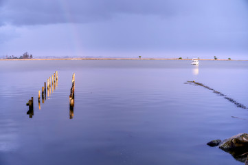 Stakes of ancient quays, mark a path on the blue waters across the lake to the rainbow on the...